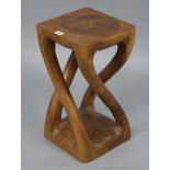 An African carved hardwood stool with four shaped supports, 10½” wide x 20” high.