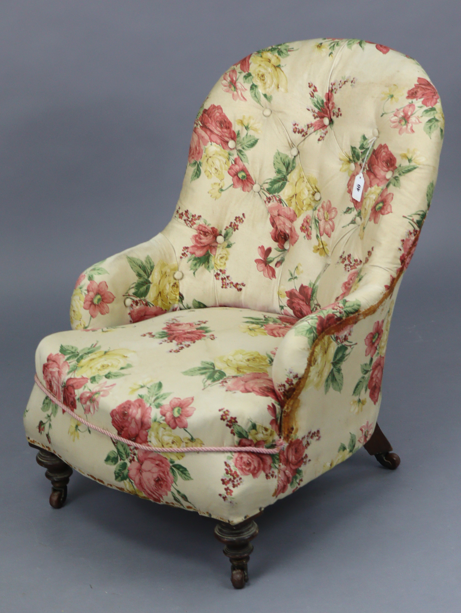 A late Victorian buttoned-back nursing chair upholstered floral material, & on short turned legs