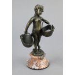 A bronzed ornament in the form of a standing girl figure holding a basket in each hand, & mounted on