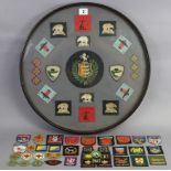 A display of twenty-one various cloth badges, in ebonised glazed circular frame; 18½” diam.;