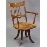 A beech spindle-back swivel desk chair with hard seat, & on four splay legs.