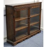 An oak bookcase with moulded frieze, fitted two shelves enclosed by pair of glazed doors, & on