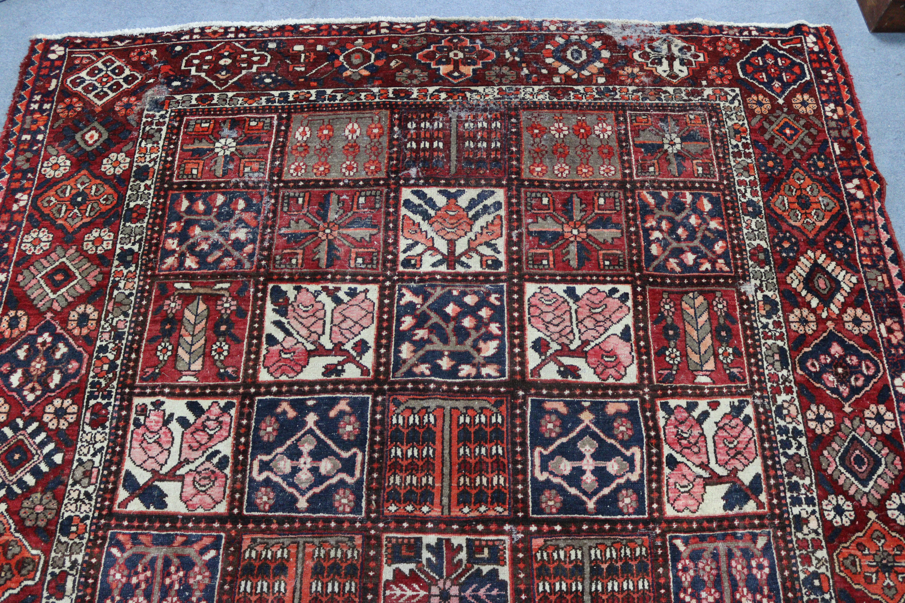 A Persian pattern carpet of crimson & deep blue ground, & with all-over repeating multi-coloured