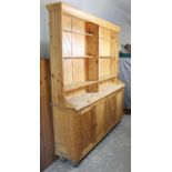 A large pine dresser, the upper part fitted six shelves above an open recess, the base with cupboard