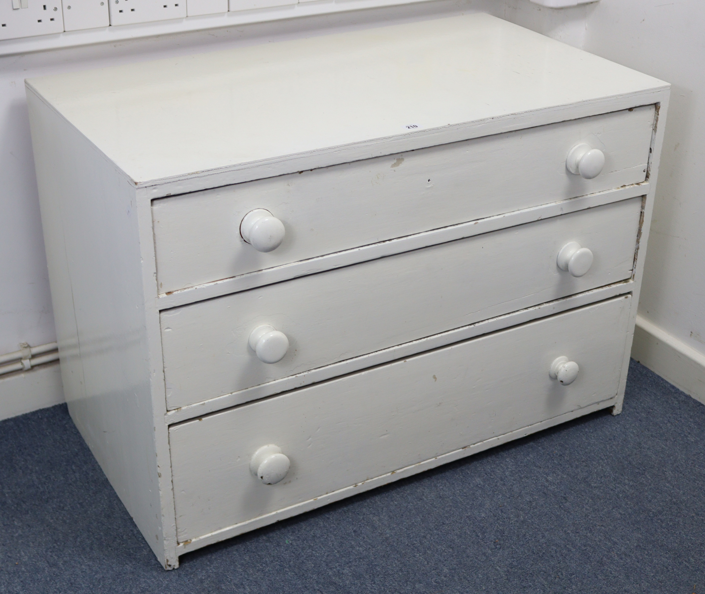 A white painted pine low chest, fitted three long graduated drawers with turned knob handles, 39”