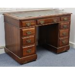 A late Victorian walnut pedestal desk inset dark green leather & fitted with an arrangement of