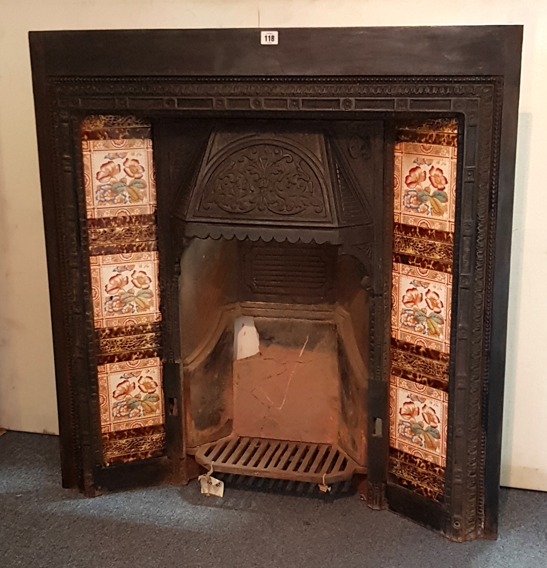 An Edwardian black painted cast-iron fire-insert six floral decorated tiles, 36”wide x 37¾” high.