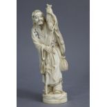 A Japanese carved ivory okimono of a fisherman, the standing figure dressed in long robes with