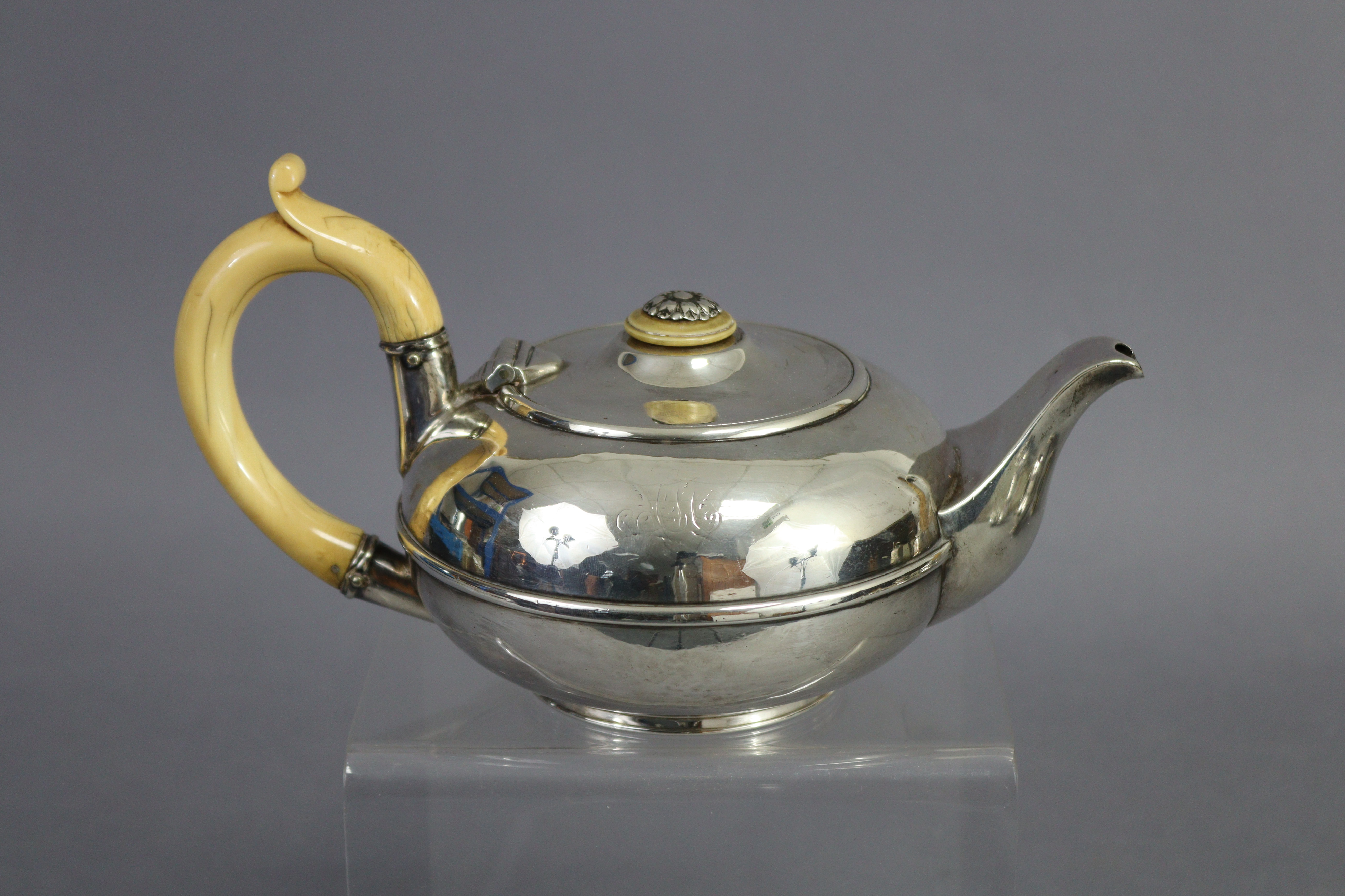 A George IV silver teapot of compressed round form, with ivory scroll handle & finial to the