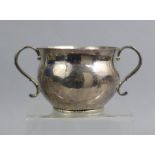 A COMMONWEALTH PERIOD SILVER PORRINGER of baluster form with two scroll handles, a chased narrow