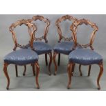 A set of four Victorian carved walnut dining chairs, with stylised foliate decoration to the pierced