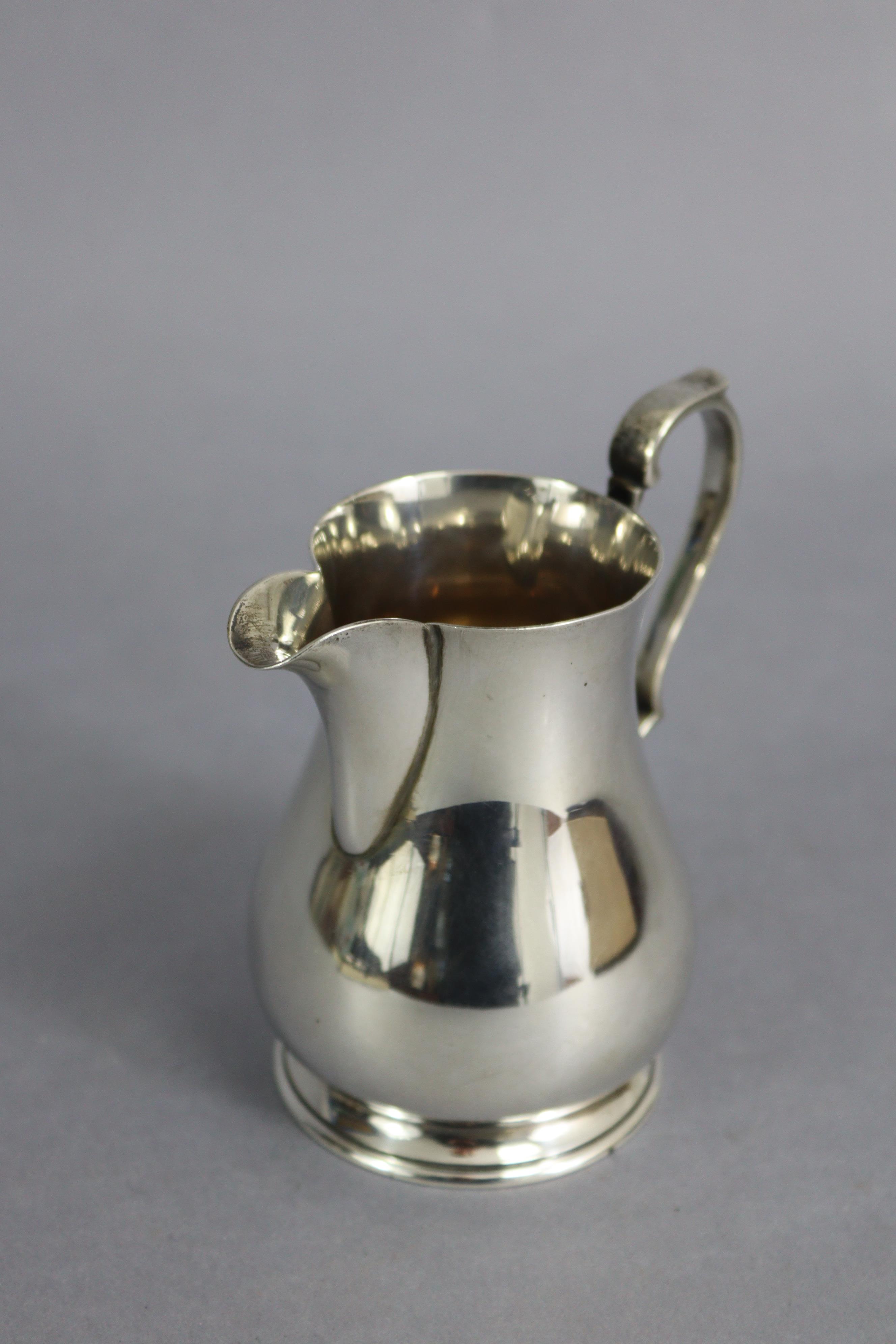 A George V silver baluster milk jug in the mid-18th century style, with scroll handle & on spread - Image 2 of 3