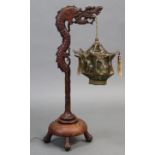 An early 20th century Chinese carved hardwood table lamp in the form of a dragon suspending a