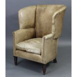 An early Victorian wing-back armchair upholstered brass-studded pale tan leather, with squab cushion