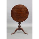 An 18th century oak tripod table with circular tilt top on baluster turned centre column & slender