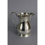 A George V silver baluster milk jug in the mid-18th century style, with scroll handle & on spread
