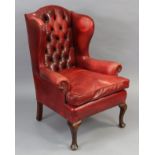 An early 20th century buttoned wing-back armchair upholstered brass-studded crimson leather, with