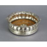 A George IV silver wine coaster with lobed baluster sides, shaped reeded foliate rim, inset turned