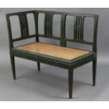 A 19th century green-painted corner settee with pierced foliate splats to the slightly curved