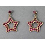 A PAIR OF RUBY PENDANT EARRINGS, each of open five-pointed star shape set twenty round-cut stones of