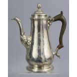 A GEORGE II SILVER COFFEE POT of slender baluster form, with engraved armorial, leaf-capped