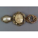 A Victorian yellow metal hollow-work brooch on intertwined scroll form, 2” wide; a similar