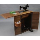 A Singer electrically operated treadle sewing machine, w.o., in mahogany-finish case enclosed by