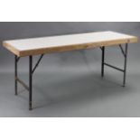 A pine frame trestle table, inset white Formica to the rectangular top, & on cast-iron fold-away