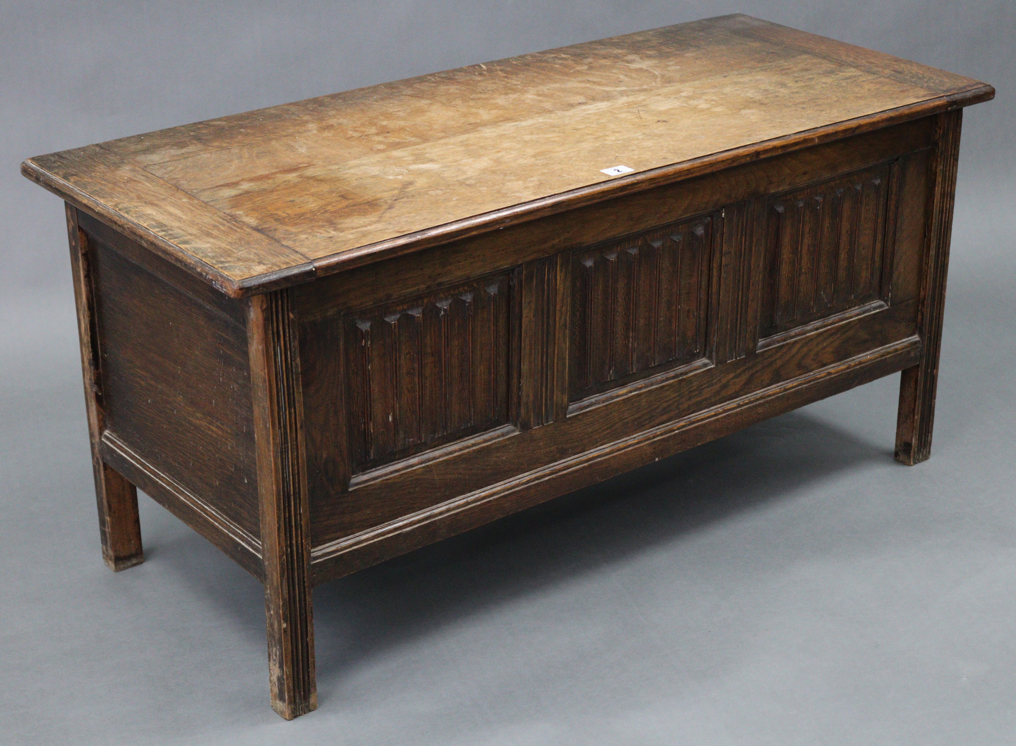 An oak coffer with hinged lift-lid, linen-fold panel front, & on short square legs, 42” wide x 20”