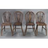 A set of four oak wheel-back dining chairs with hard seats, & on turned legs with spindle stretchers