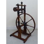 A mid 19thC fruitwood freestanding treadle spinning wheel 22''dia with ornately carved,