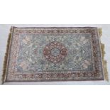 A silk and woollen rug, decorated with a central serpentine outlined floral motif,