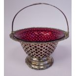 An Edwardian silver framed sugar basket with a cranberry glass liner, decoratively pierced sides,