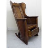 An 18thC and later oak and elm panelled and angled wingback lambing chair with enclosed,