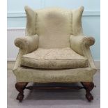 An early 20thC Georgian inspired, upholstered wingback chair with a cushion seat and scrolled arms,