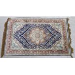 A silk and woollen rug, decorated with a central serpentine outlined floral motif,