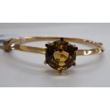 A 9ct rose gold hollow hinged bangle, claw set with a citrine,