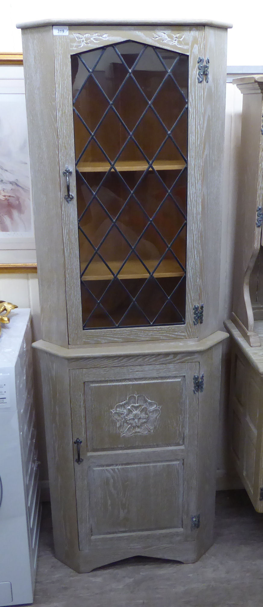 A modern washed oak corner cupboard, the top with a glazed door, over a panelled door,