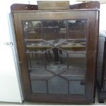 An early 20thC mahogany corner cabinet with a single glazed door,