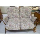 An Ercol hoop and spindle back, stained beech and elm framed two person settee,