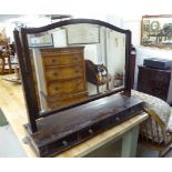 An early 20thC mahogany toilet mirror, the shaped bevelled plate set between pivoting horns,