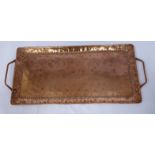 An Arts & Crafts twin handled copper tray with spot-hammered decoration to the border bearing the