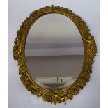 A late Victorian mirror, the oval, bevelled plate set in a cast gilt metal frame,