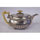 A George III silver teapot of squat, demi-reeded form with shell cast and other embellishment,