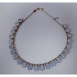 A gold coloured metal necklace, claw set with uniform oval smokey coloured oval stones,