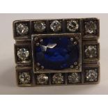 A white metal signet style ring, block set with a blue stone,