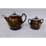 A Royal Doulton treacle glazed stoneware teapot, bearing a moulded study of an elderly couple,