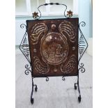 An early 20thC Arts & Crafts burnished, hammered copper and black painted, ornately wrought iron,