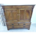 An early 19thC (possible Welsh) oak and mahogany linen cupboard with a pair of panelled doors,