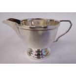 A silver cream jug of circular bowl design with a loop wire handle,